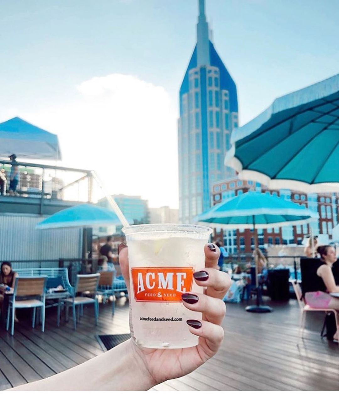 Holding a drink of Acme's rooftop