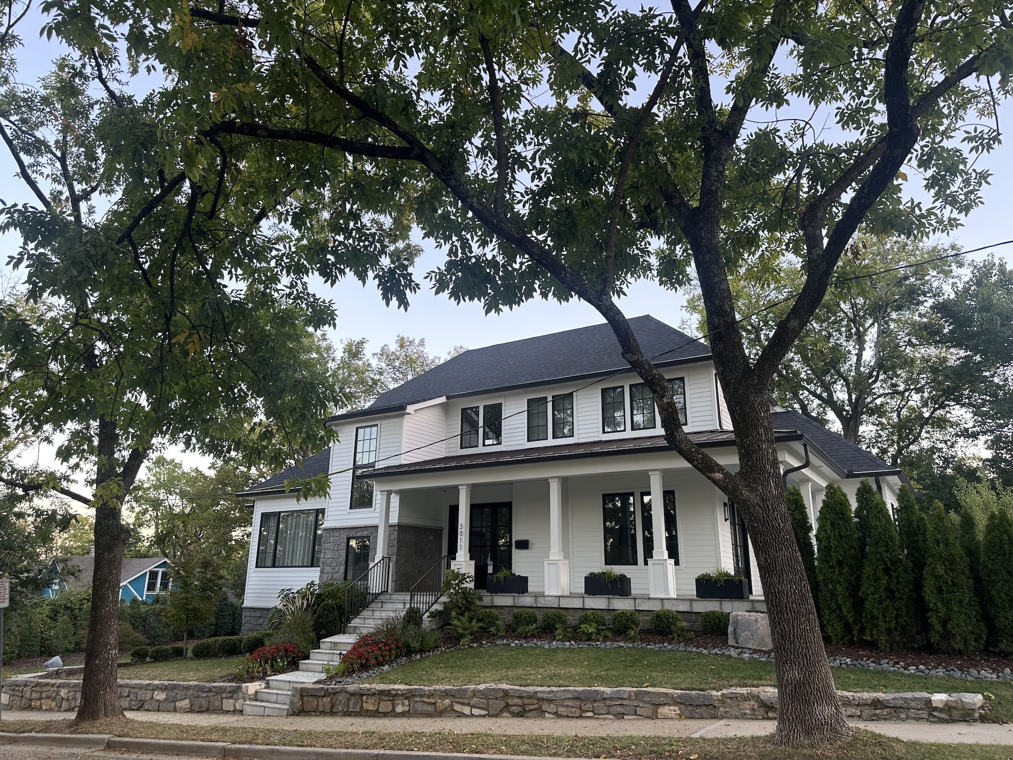 A nice house with big trees and a sidewalk