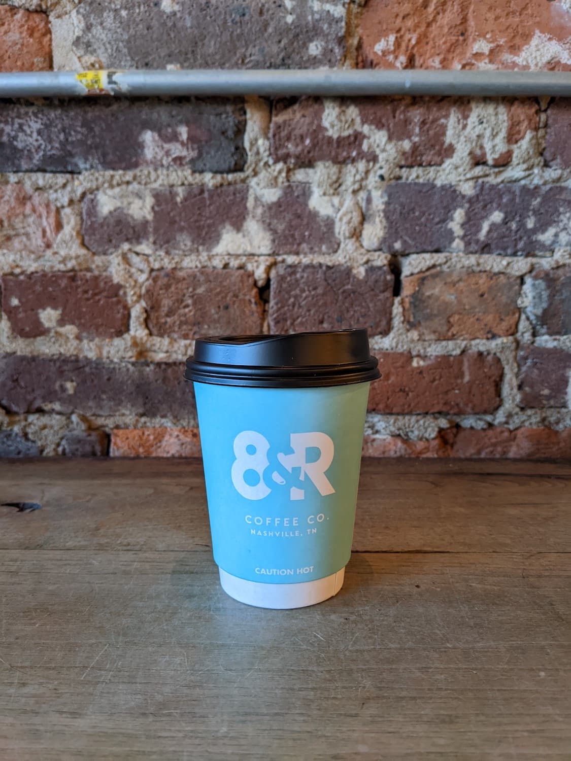 8th & Roast to go cup in front of brick wall
